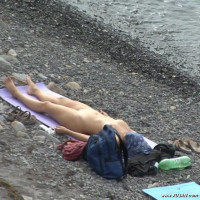 Naked babe tanning in front of a couple