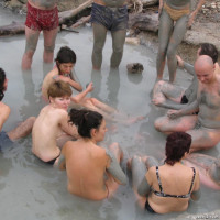Group of young nudists taking mud bath