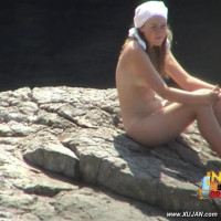 Hot babe sits naked on a big rock