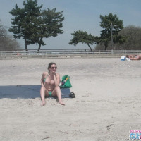 Busty brunette takes sunbath on public beach