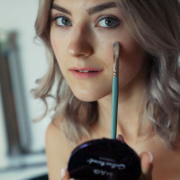 Platinum blonde teen Eva Elfie does her makeup during a nude modelling gig