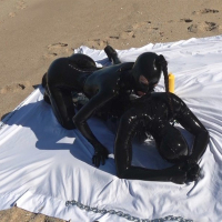 Kinky Latex Lara gets talked into jerking off a dick on the beach