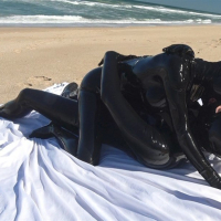 Kinky Latex Lara gets talked into jerking off a dick on the beach