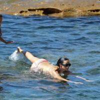 Demi Harman showing off her curvy body in a striped red bikini at the beach in S