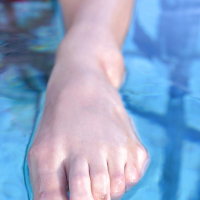 Solo babe Loulou Petite showing off bare feet and legs outdoors beside pool