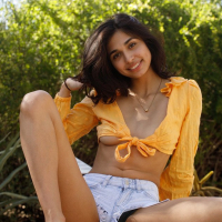 Latina Reina Rae poses wearing denim shorts and sexy top