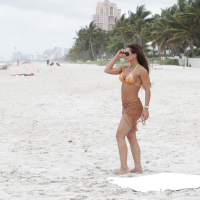 Mature woman Nina Dolci letting firm tits free from bikini on beach