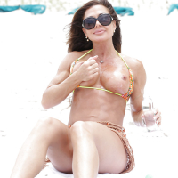 Mature woman Nina Dolci letting firm tits free from bikini on beach