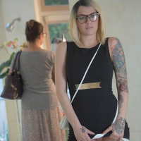 Tattooed female Emma Mae revealing bald vagina underneath black dress