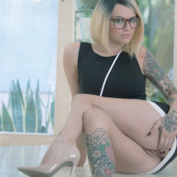 Tattooed female Emma Mae revealing bald vagina underneath black dress