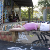 Cute Lil Candy poses outdoors with graffiti and gets horny