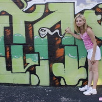 Cute Lil Candy poses outdoors with graffiti and gets horny