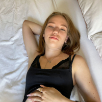 Solo Maya Sinn gently fingering her shaved pussy on the bed