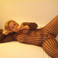 Chubby Blondy poses on a Bed in a Fishnet Outfit