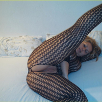 Chubby Blondy poses on a Bed in a Fishnet Outfit