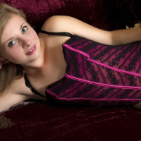 Lil Candy wears a pink and black corset and fucks herself