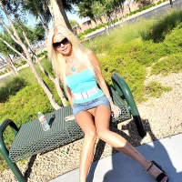 Barbi Sinclair wears glasses as she poses outdoors in high heels and mini skirt