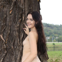Longhaired brunette Anie Darling poses in a hot photoshoot by the tree