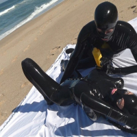 Kinky Latex Lara gets talked into jerking off a dick on the beach
