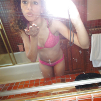 Curlyhaired latina slipping off her pink lingerie and making selfies