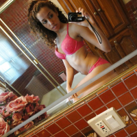 Curlyhaired latina slipping off her pink lingerie and making selfies